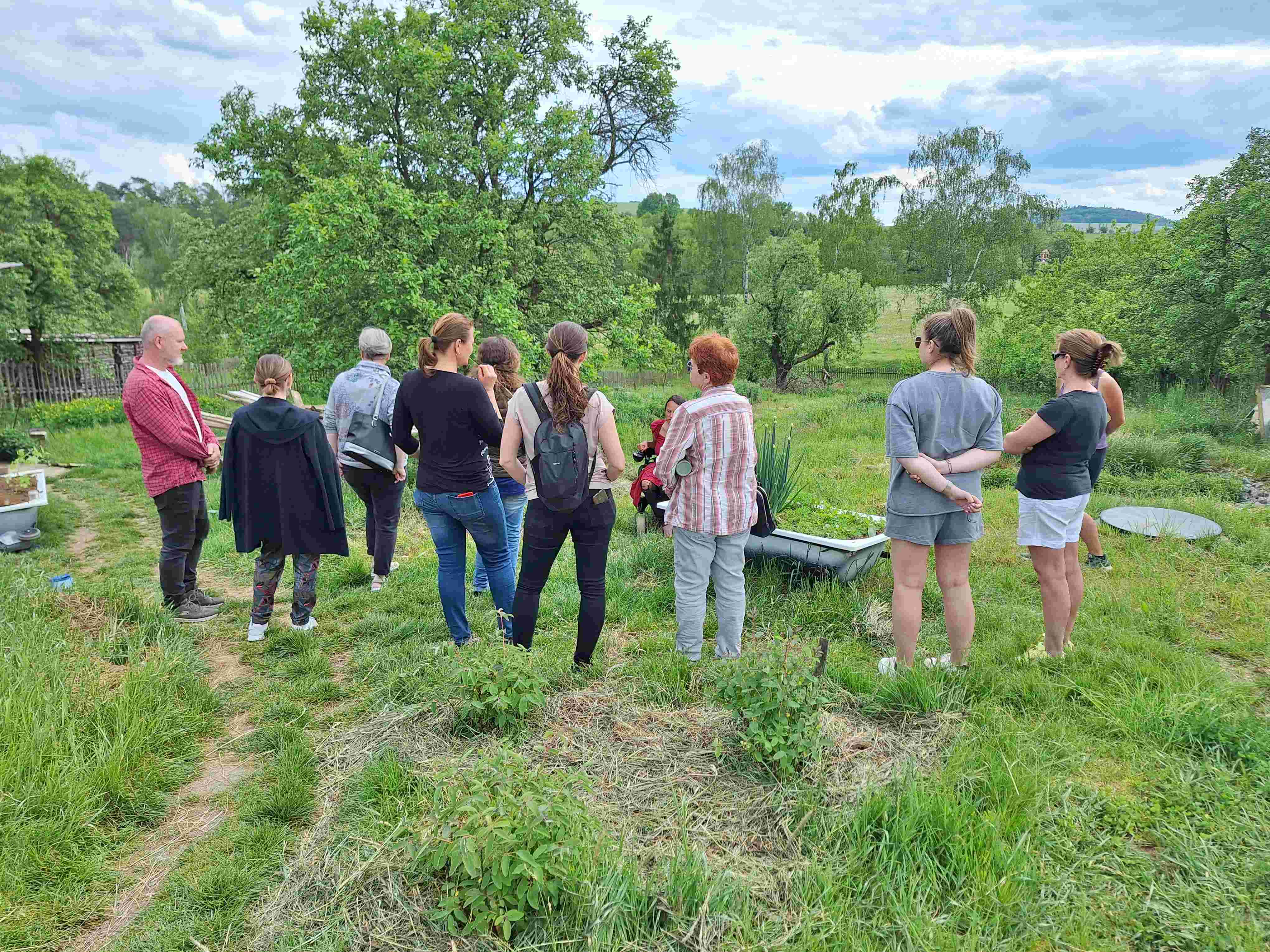 Skupina lidí kouká do sadu